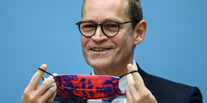 Das Foto zeigt Regierungschef Michael Müller von der SPD mit einem Mund-Nase-Schutz in beiden Händen.