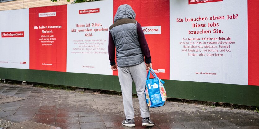 Ein Mann schaut sich ein Plakat an, auf dem für ein Jobportal geworben wird