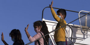 Drei Kinder winken von einer Flugzeugtreppe