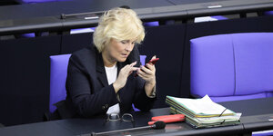 Christine Lambrecht sitzt im Deutschen Bundestag und blickt auf ihr Smartphone.
