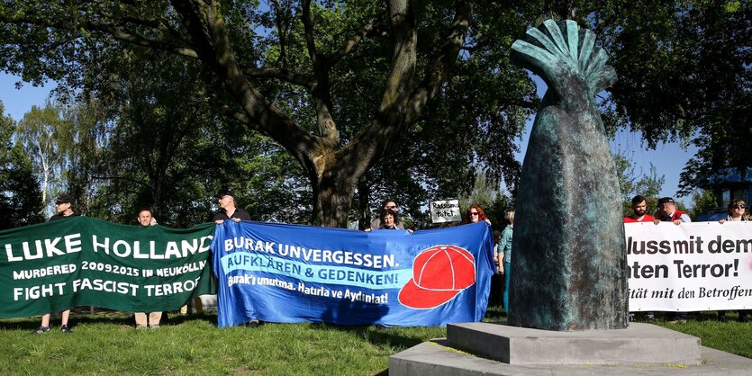 Eine Demonstration steht vor einem Denkmal, das an Burak Bektas erinnert