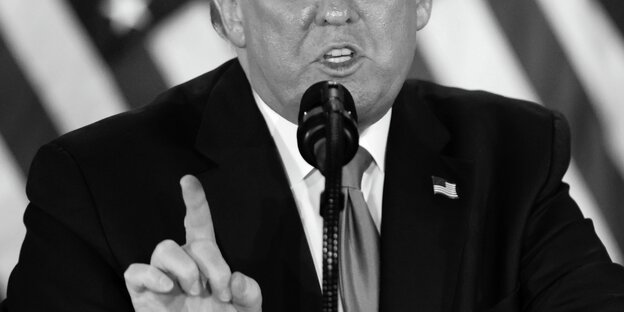 Ein Bild in Schwarz Weiß von Trump vor einem Mikrophon