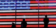 Schattenriss von Menschen vor einer großen Projektion mit der US Flagge