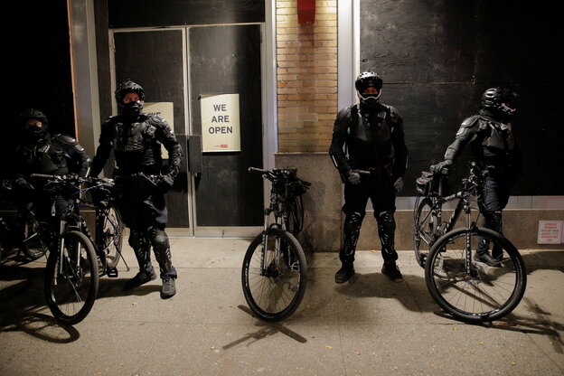 Police officers are standing with bicycles at the entrance to a barricaded shop