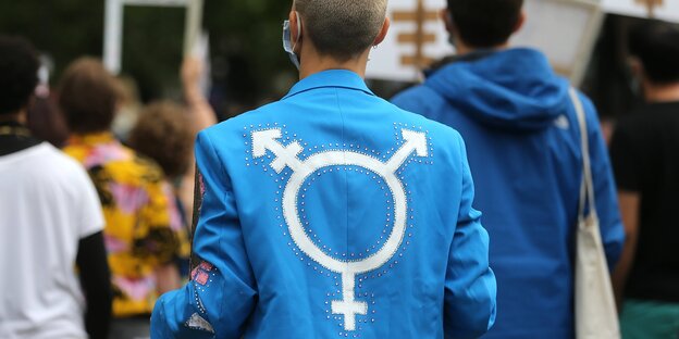 Ein Mensch trägt eine blaue Jacke mit dem Transgender-Symbol