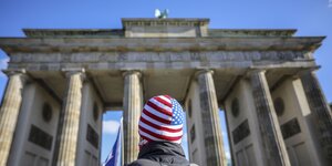 Ein Mann mit USA-Muetze vor dem Brandenburger Tor