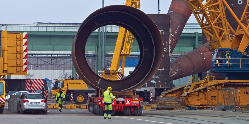 Arbeiter transportieren eine Röhre auf einem Spezialfahrzeug.