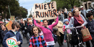 auf einer Demonstration hält eine junge Frau ein Schild hoch: Miete runter