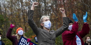 Drei Frauen mit hochgestreckten Armen und Joe Biden Plakat während einer Demonstration
