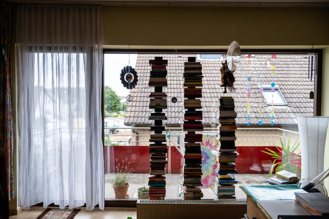 Bücherstapel am Fenster, eine kleine Hexe baumelt von der Decke