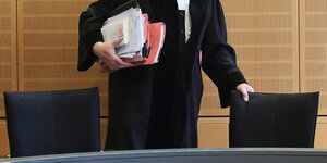 Ein Richter rückt sich zum Auftakt eines Mordprozesses in einem Verhandlungssaal seinen Stuhl zurecht.
