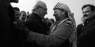 Honecker im Mantel links umarmt Arafat (mit Kufiya auf dem Kopf)