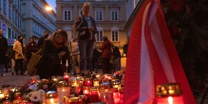Zwei Frauen zünden an der Gedenkstätte für die Opfer des Terroranschlags in Wien Kerzen an
