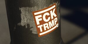 Aufkleber mit "FCK TRMP" an einem Laternenpfahl