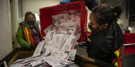 Eine Wahlhelferin schüttet eine Box mit Wahlbriefen aus