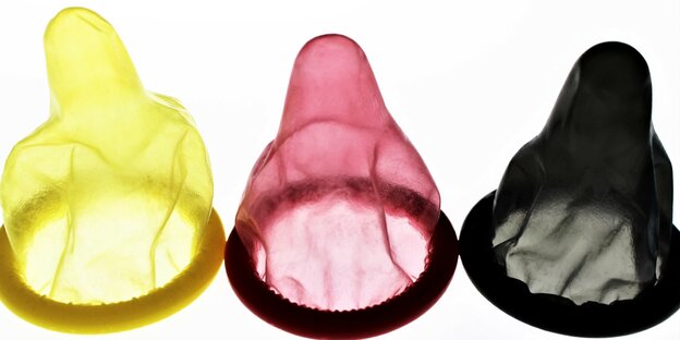 drei Kondome ausgepackt in den Farben gelb, rot und schwarz