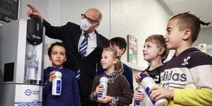 Schulkinder und Ties Rabe stehen neben einem Wasserspender.