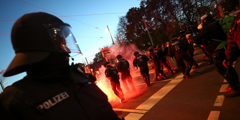 Polizeibeamte in Schutzausrüstung werden angeleuchtet von bengalischen feuern