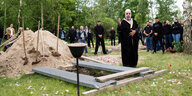 Ein Imam steht an einem offenen Grab