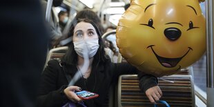 Eine Frau in der Métro mit einem Luftballon in Form eines lachenden Bärenegesichts