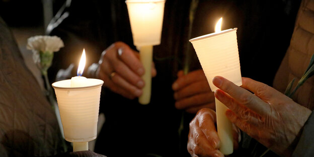 Mehrere Menschen halten Kerzen in der Dunkelheit