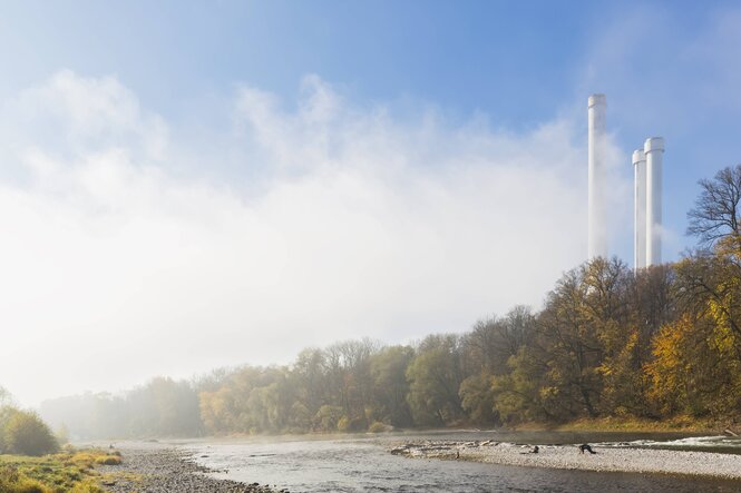 Isar mit Uferböschung, dahinter die schlanken Türme des Kraftwerks