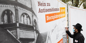 Der Rabbiner Shmuel Havlin unterschreibt auf einem Plakat mit dem Text "Nein zu Antisemitismus - Ja zur Bornplatzsynagoge"