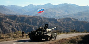 Ein russischer Soldat läuft neben einem Panzer.