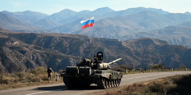 Ein russischer Soldat läuft neben einem Panzer.