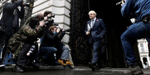 Boris Johnson verlässt das Foreign and Commonwealth Office und wird von mehreren Fotografen fotografiert.