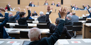 Abstimmung im Landtag von Baden-Württemberg. Menschen heben ihre Hände