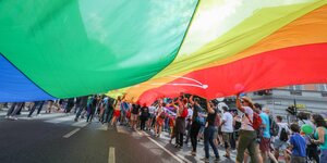 Die Gay Pride Parade im Juli 2018 in Budapest - Demonstranten und Demonstrantinnen laufen mit einer großen Regenbogen-fahne durch die Strassen-