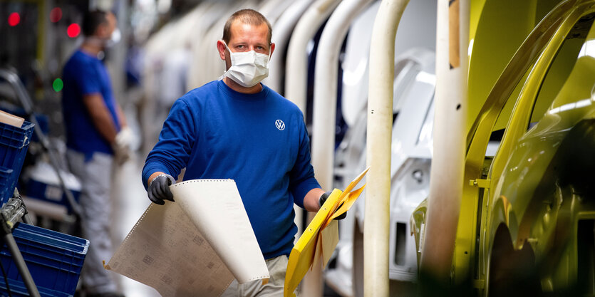 Ein Mann im VW Werk Wolfsburg traegt Mund-Nasenschutz in der Fertigungsstrasse.