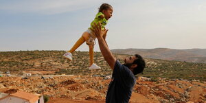 Ein Vater im syrischen Idlib wirft sein kleines Kind freudig in die Luft