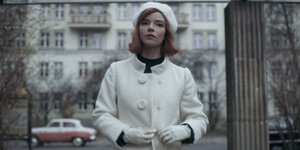 Frau in weißem Mantel vor Häusern an der Katl-Marx-Allee in Berlin