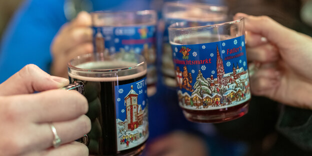 Glühwein-Tassen werden zum Anstoßen erhoben Glühwein-Tassen werden zum Anstoßen erhoben