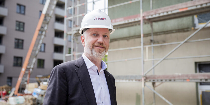 Ein Mann steht mit Bauhelm auf einer Baustelle