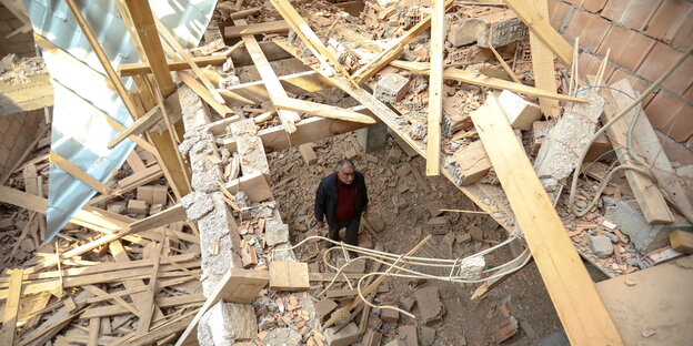 Ein Mann steht in den Trümmern seines Hauses