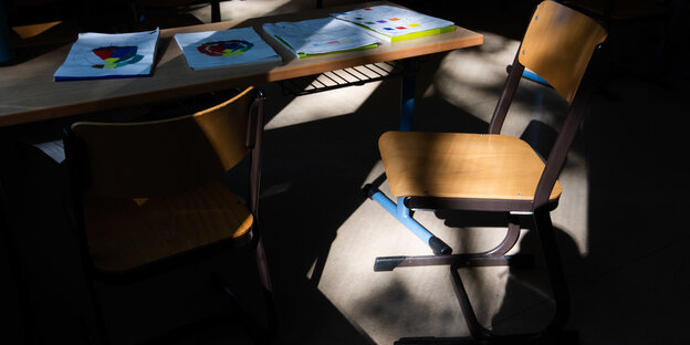 Licht scheint auf einen Stuhl im Klassenzimmer, der Rest liegt im Dunkeln