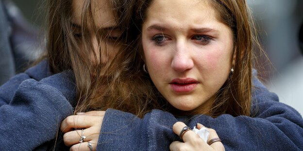 Zwei trauernde junge Frauem umarmen sich