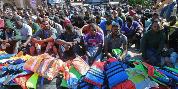 Migranten, die vor ihrer Flucht nach Europa abgehalten wurden sitzen in einem Checkoint in Al-Chums in Libyen fest.