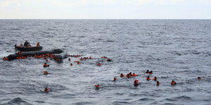 Die spanischen NGO Open Arms mit einem Motorbot sammlelt umhertreibende Menschen mit orangen Schwimmwesten im Mittelmeer auf.