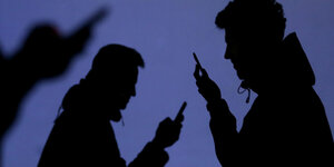Silhouetten von drei Mobilfunknutzern mit Smartphones in der Hand