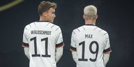 Zwei Fußballspieler der Nationalelf stehen mit dem Rücken zugewandt auf dem Fußballplatz