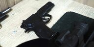 Eine schwarze Pistole liegt auf einem Holztisch