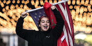 Eine Frau hält die Flagge der Vereinigten Staaten von Amerika in Siegerpose in der Hand