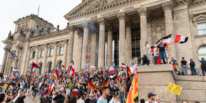 Viele Menschen mit Reichsflaggen sind auf den Stufen des Reichstags in Berlin