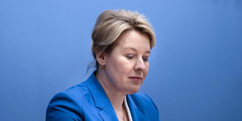 Politikerin Franziska Giffey mit nach unten gerichteten Blick in einem blauen Blazer vor einer blauen Wand