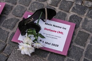 Ein Schuh und eine Blume liegen auf einer Todesanzeige