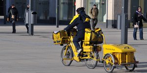 Eine Postbotin auf einem Rad mit Anhänger